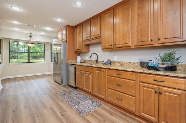 6060 Bud Moulton Rd, Crestview, FL 32536 - kitchen with stainless steel appliances, light wood-style floors, brown cabinets, light stone counters, and hanging light fixtures