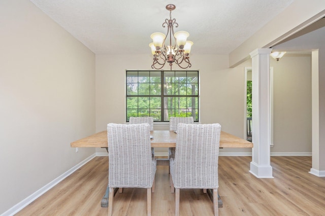 6060 Bud Moulton Rd, Crestview, FL 32536 - dining space featuring light wood-type flooring, a chandelier, a textured ceiling, and ornate columns