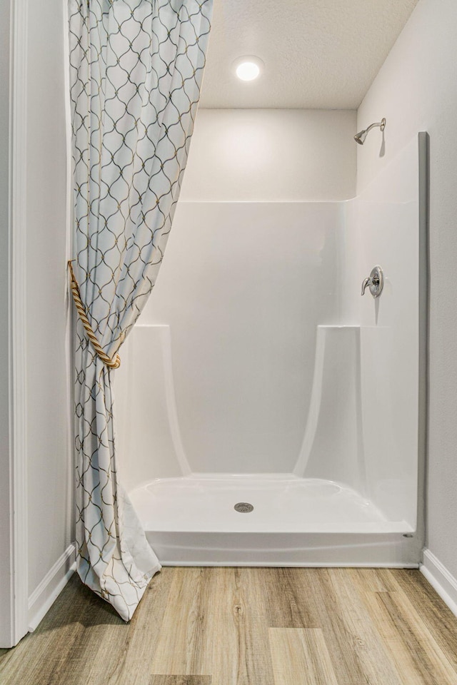 2889A Patriot Ridge Dr, Crestview, FL 32539 - full bath with wood finished floors, a shower with shower curtain, baseboards, and a textured ceiling