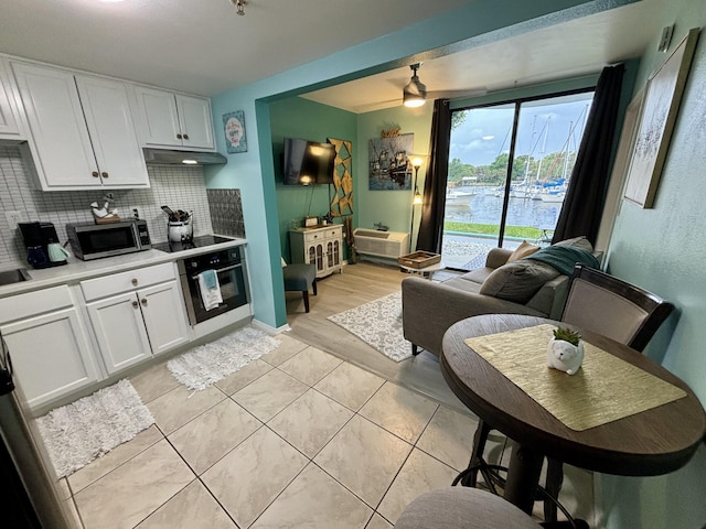 201 S Stillman St Unit 107, Pensacola, FL 32505 - kitchen with stainless steel appliances, tasteful backsplash, white cabinetry, under cabinet range hood, and light countertops