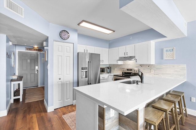 780 Sundial Ct Unit 2001, Fort Walton Beach, FL 32548 - kitchen featuring appliances with stainless steel finishes, a peninsula, under cabinet range hood, a kitchen breakfast bar, and white cabinetry