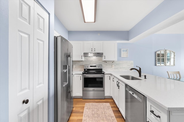 780 Sundial Ct Unit 2001, Fort Walton Beach, FL 32548 - kitchen with stainless steel appliances, a peninsula, under cabinet range hood, light wood-style floors, and white cabinetry