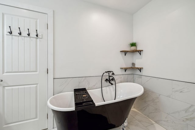 736 Sandpiper Pl Unit 10525, Miramar Beach, FL 32550 - bathroom with marble finish floors, a freestanding tub, tile walls, and wainscoting