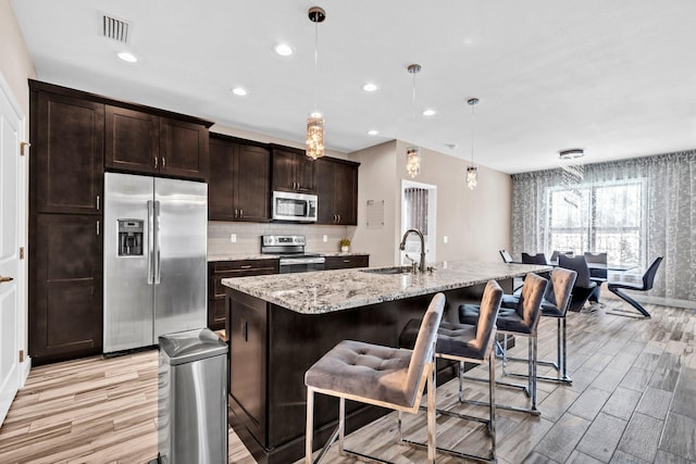 1369 N Beal Ext, Fort Walton Beach, FL 32547 - kitchen with stainless steel appliances, light wood-style flooring, a kitchen bar, recessed lighting, and light stone countertops