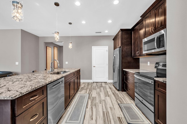 1369 N Beal Ext, Fort Walton Beach, FL 32547 - kitchen with appliances with stainless steel finishes, light wood-type flooring, dark brown cabinets, pendant lighting, and a center island with sink