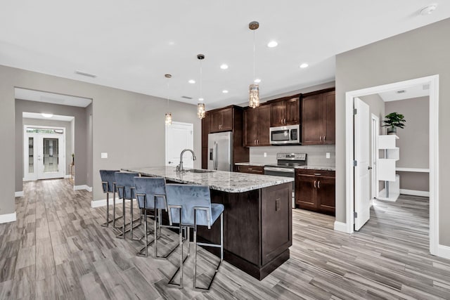 1369 N Beal Ext, Fort Walton Beach, FL 32547 - kitchen with stainless steel appliances, light wood-style flooring, a center island with sink, dark brown cabinets, and recessed lighting