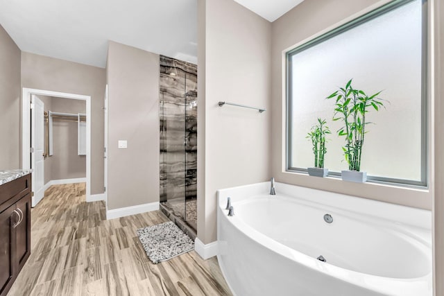 1369 N Beal Ext, Fort Walton Beach, FL 32547 - bathroom with a garden tub, vanity, a stall shower, a spacious closet, and wood finished floors