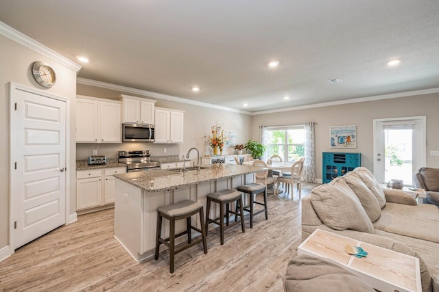 364 Lightning Bug Ln, Freeport, FL 32439 - kitchen featuring appliances with stainless steel finishes, open floor plan, a kitchen bar, ornamental molding, and light stone countertops