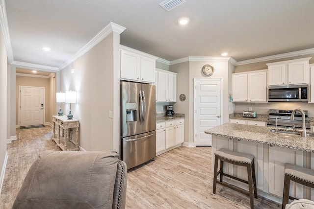 364 Lightning Bug Ln, Freeport, FL 32439 - kitchen with appliances with stainless steel finishes, light wood-style flooring, a kitchen breakfast bar, white cabinets, and ornamental molding