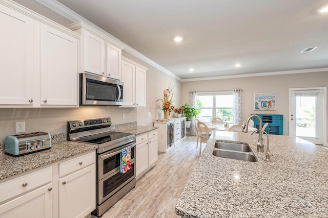 364 Lightning Bug Ln, Freeport, FL 32439 - kitchen featuring appliances with stainless steel finishes, crown molding, white cabinetry, light wood finished floors, and light stone counters