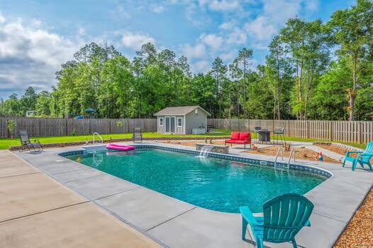 2405 Dakota Way, Crestview, FL 32536 - view of swimming pool with a patio area, a fenced backyard, a storage unit, and view of wooded area