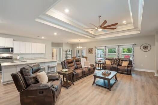 2405 Dakota Way, Crestview, FL 32536 - living room featuring a raised ceiling, ceiling fan, light wood-type flooring, recessed lighting, and a chandelier