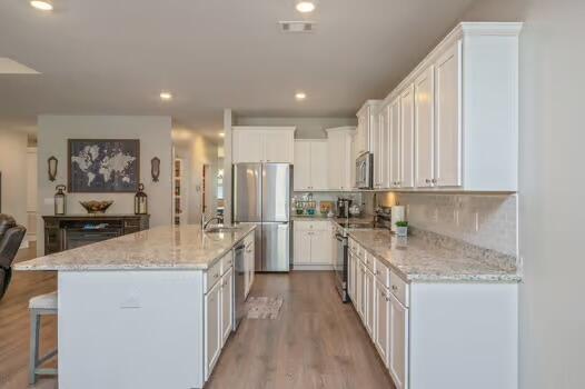 2405 Dakota Way, Crestview, FL 32536 - kitchen featuring stainless steel appliances, white cabinetry, light wood-type flooring, a kitchen breakfast bar, and recessed lighting