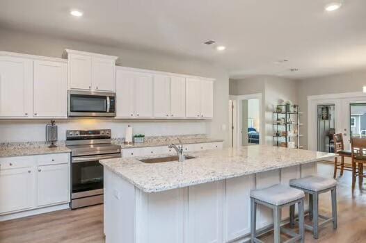 2405 Dakota Way, Crestview, FL 32536 - kitchen featuring stainless steel appliances, white cabinetry, an island with sink, light wood-style floors, and recessed lighting