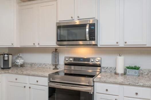 2405 Dakota Way, Crestview, FL 32536 - kitchen with stainless steel appliances, white cabinets, and light stone countertops