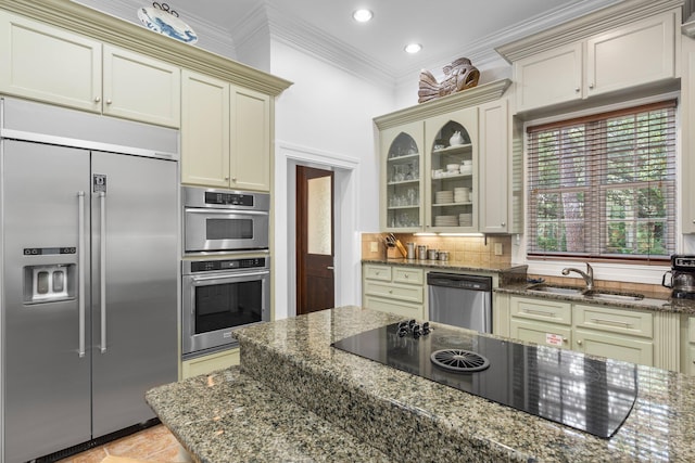 176 Rue Martine, Miramar Beach, FL 32550 - kitchen with appliances with stainless steel finishes, cream cabinetry, crown molding, glass insert cabinets, and dark stone counters