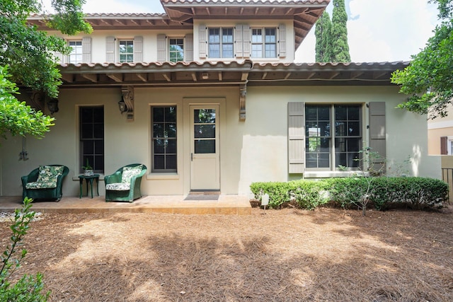 176 Rue Martine, Miramar Beach, FL 32550 - rear view of house with stucco siding, a tile roof, and covered porch