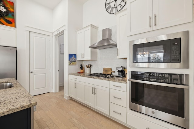 234 Grande Pointe Cir, Inlet Beach, FL 32461 - kitchen featuring stainless steel appliances, wall chimney exhaust hood, tasteful backsplash, light wood finished floors, and light stone countertops