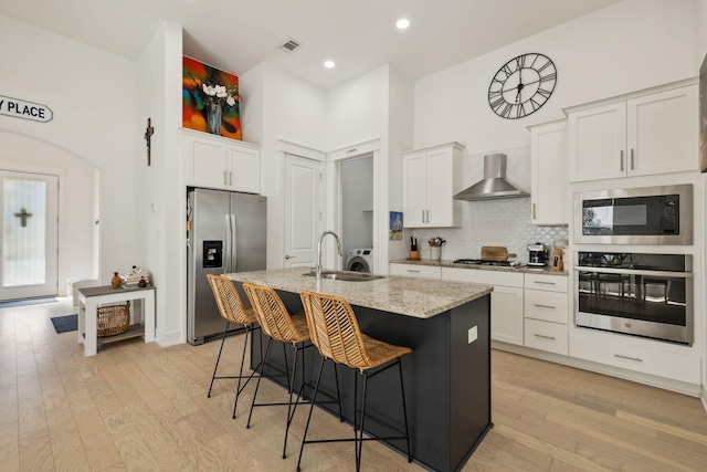 234 Grande Pointe Cir, Inlet Beach, FL 32461 - kitchen with appliances with stainless steel finishes, wall chimney range hood, a high ceiling, a kitchen island with sink, and white cabinets