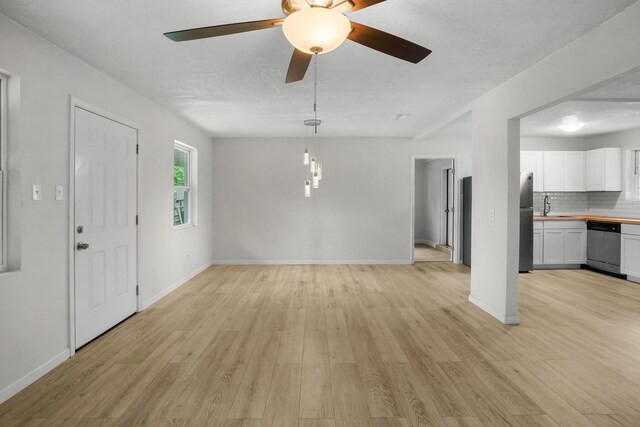 1023 W Webster Dr, Pensacola, FL 32505 - unfurnished living room with light wood-type flooring, a ceiling fan, and a textured ceiling
