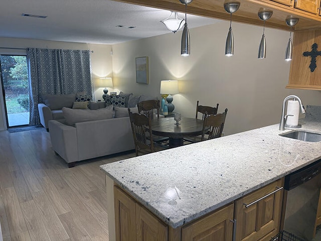 3861 Indian Trl Unit 104, Destin, FL 32541 - kitchen with stainless steel dishwasher, light wood-style flooring, brown cabinets, and open floor plan