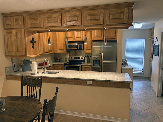3861 Indian Trl Unit 104, Destin, FL 32541 - kitchen featuring appliances with stainless steel finishes, a peninsula, brown cabinets, and light stone counters
