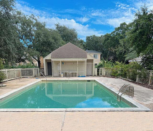 3861 Indian Trl Unit 104, Destin, FL 32541 - view of pool featuring a patio, view of wooded area, and an outbuilding