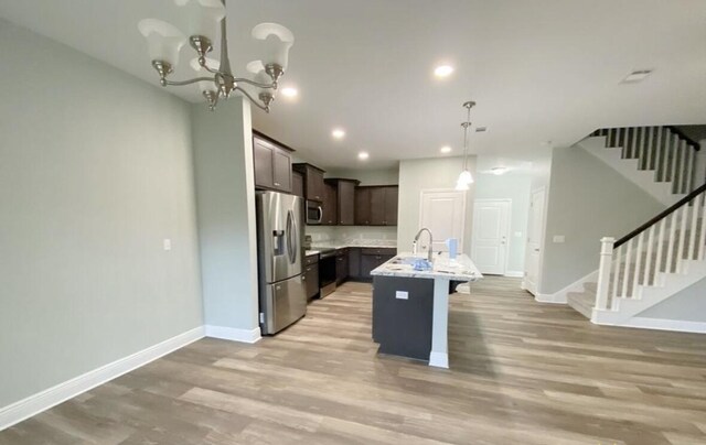 196 Johnson Ct, Crestview, FL 32536 - kitchen featuring appliances with stainless steel finishes, dark brown cabinetry, light wood-type flooring, a breakfast bar, and a center island with sink