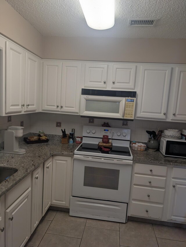 1809 Madelons Path, Fort Walton Beach, FL 32547 - kitchen with white appliances, a textured ceiling, light tile patterned floors, white cabinets, and light stone countertops