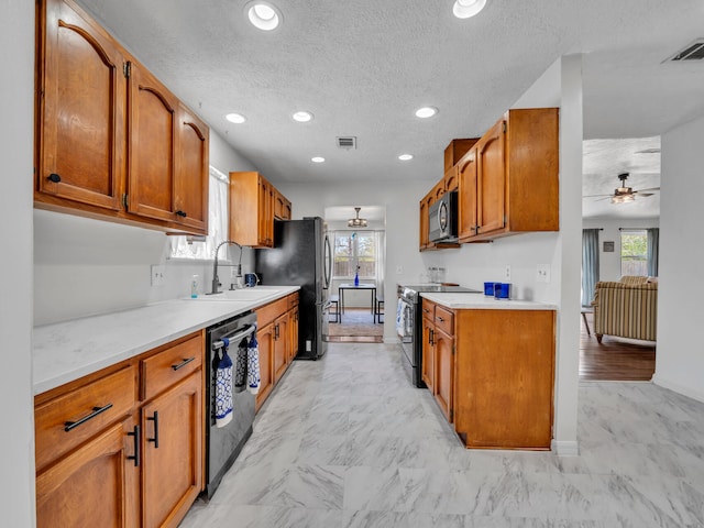 2016 E Three Putt Ln, Panama City, FL 32404 - kitchen with stainless steel appliances, ceiling fan, healthy amount of natural light, brown cabinets, and a textured ceiling
