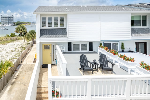 415 Gulf Shore Dr Unit 1, Destin, FL 32541 - rear view of property with a shingled roof, a fenced backyard, a water view, and a patio