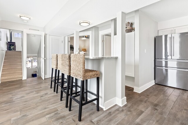 415 Gulf Shore Dr Unit 1, Destin, FL 32541 - kitchen with freestanding refrigerator, light wood finished floors, a breakfast bar area, light stone countertops, and white cabinetry