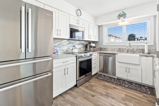 415 Gulf Shore Dr Unit 1, Destin, FL 32541 - kitchen featuring appliances with stainless steel finishes, white cabinets, light wood-style flooring, and light stone counters