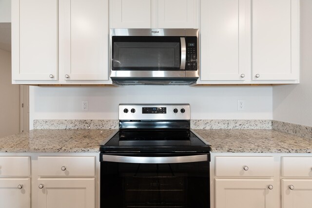 919 Sandbar Loop, Crestview, FL 32539 - kitchen featuring stainless steel microwave, range with electric stovetop, white cabinetry, and light stone counters