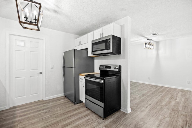 4352 Watkins St, Pace, FL 32571 - kitchen featuring appliances with stainless steel finishes, a chandelier, light wood-type flooring, white cabinetry, and a textured ceiling