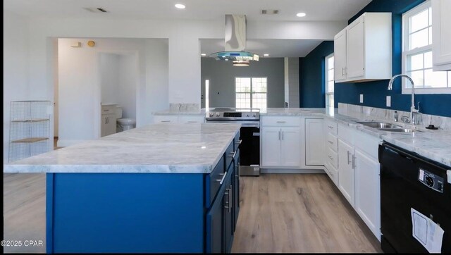 7202 Ranier St, Panama City, FL 32404 - kitchen with black dishwasher, electric range, blue cabinetry, light wood finished floors, and light stone countertops