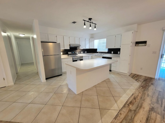 6868 E Bay Blvd, Navarre, FL 32566 - kitchen with appliances with stainless steel finishes, white cabinets, light countertops, a center island, and under cabinet range hood