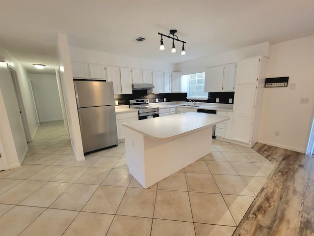 6868 E Bay Blvd, Navarre, FL 32566 - kitchen with appliances with stainless steel finishes, under cabinet range hood, white cabinetry, light countertops, and a kitchen island