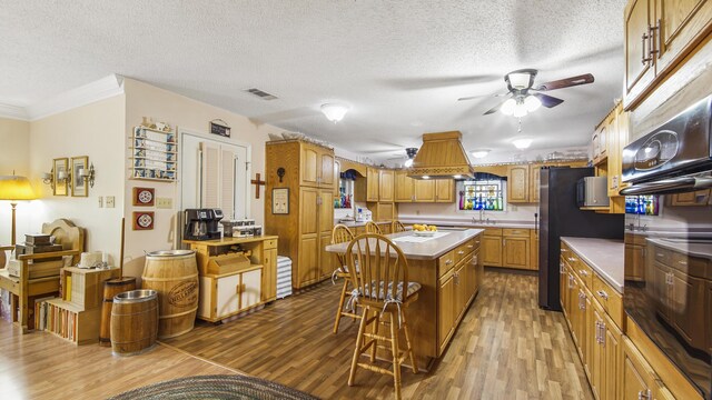4936 Grassy Pond Rd, Chipley, FL 32428 - kitchen featuring a ceiling fan, a breakfast bar area, wood finished floors, a center island, and crown molding