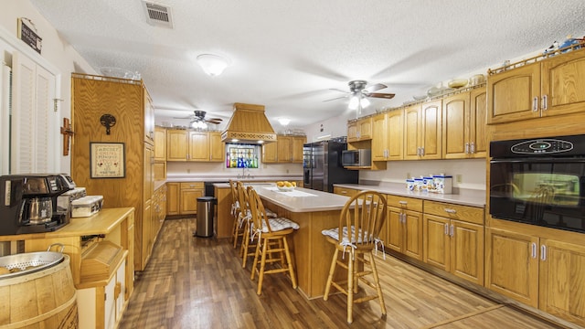 4936 Grassy Pond Rd, Chipley, FL 32428 - kitchen with black appliances, a ceiling fan, custom exhaust hood, light wood-style floors, and a textured ceiling
