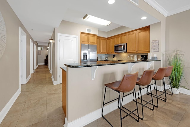 1150 Santa Rosa Blvd Unit 317, Fort Walton Beach, FL 32548 - kitchen with stainless steel appliances, backsplash, dark stone counters, a kitchen bar, and a peninsula