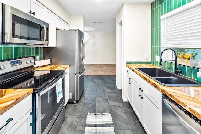 4276 Calinda Ln Apt 138, Niceville, FL 32578 - kitchen with appliances with stainless steel finishes, wooden counters, white cabinets, and backsplash