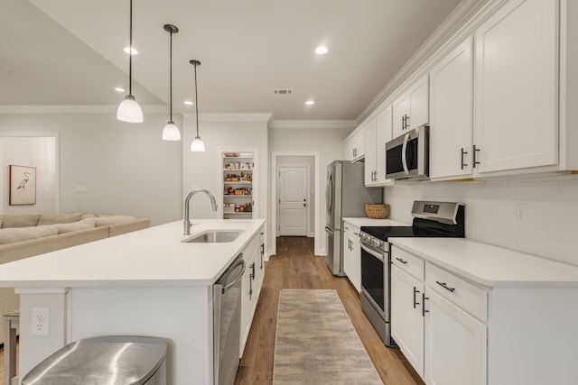 124 Apollo Ave, Freeport, FL 32439 - kitchen featuring appliances with stainless steel finishes, an island with sink, crown molding, light wood-style flooring, and white cabinetry