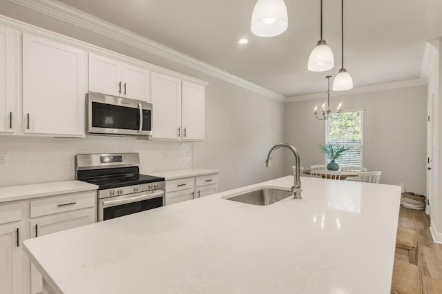 124 Apollo Ave, Freeport, FL 32439 - kitchen featuring stainless steel appliances, a center island with sink, ornamental molding, light wood finished floors, and white cabinetry