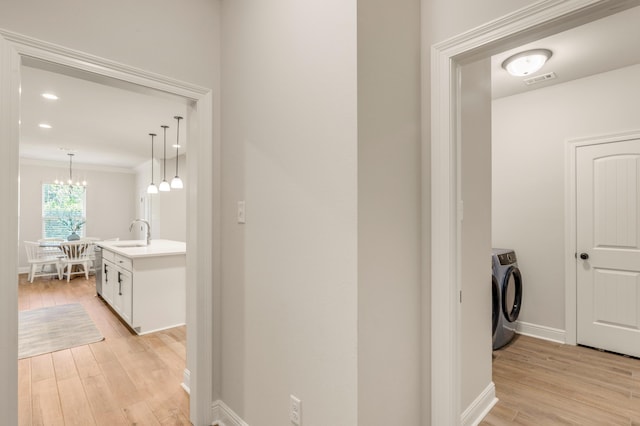 124 Apollo Ave, Freeport, FL 32439 - hallway featuring washer and dryer, light wood-style flooring, a chandelier, and ornamental molding