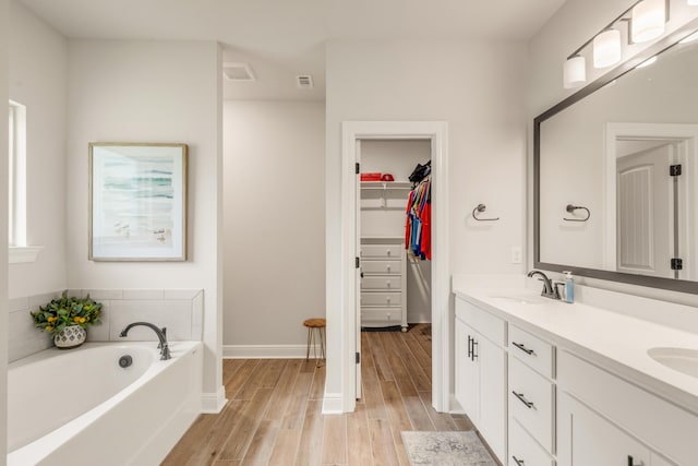 124 Apollo Ave, Freeport, FL 32439 - bathroom with double vanity, wood finished floors, a garden tub, and a spacious closet