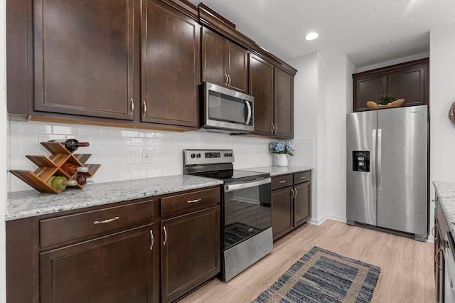 8668 Shell Sink Dr, Panama City Beach, FL 32413 - kitchen featuring appliances with stainless steel finishes, dark brown cabinetry, light wood-type flooring, decorative backsplash, and recessed lighting