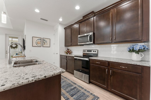 8668 Shell Sink Dr, Panama City Beach, FL 32413 - kitchen featuring stainless steel appliances, light wood-style floors, tasteful backsplash, and recessed lighting