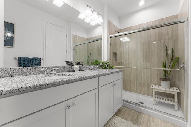 8668 Shell Sink Dr, Panama City Beach, FL 32413 - bathroom with double vanity, a stall shower, and wood finished floors