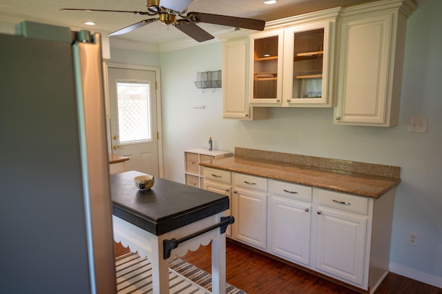 3180 Palmetta Ave, Crestview, FL 32539 - kitchen featuring freestanding refrigerator, dark wood-style flooring, ceiling fan, glass insert cabinets, and white cabinets